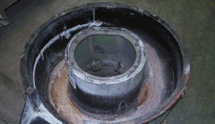 Vibratory bowl before relining, with the old lining stripped out and the processing channel worn and corroded